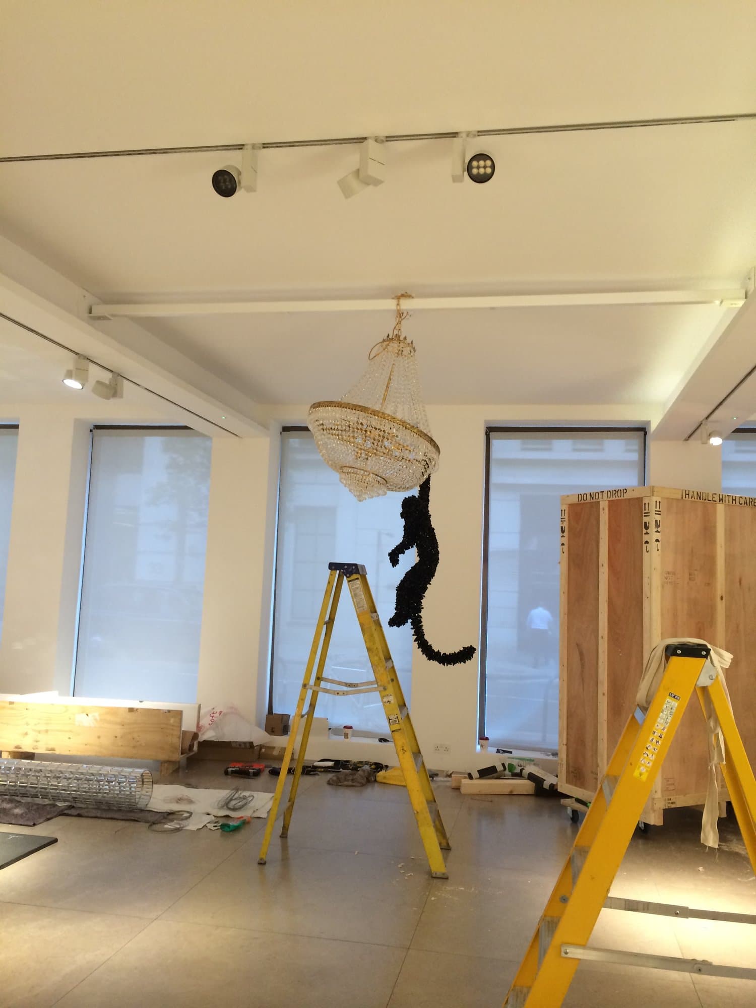Crystal chandelier and sculpture being installed in the gallery