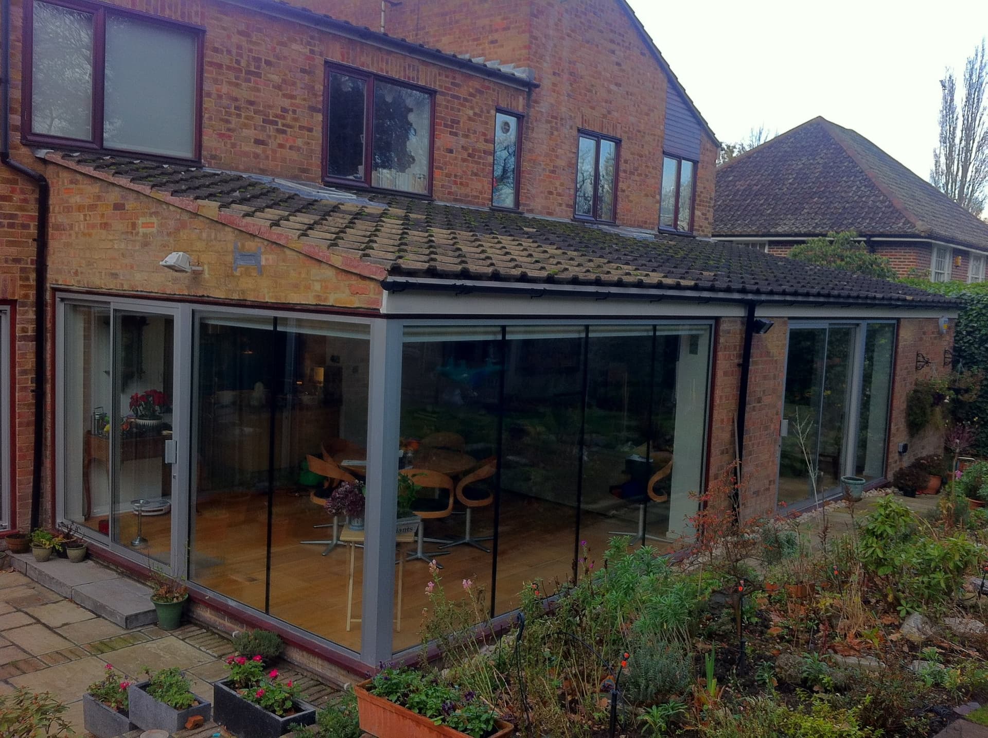 Single-storey glazed extension with frameless glass corner opening onto the garden