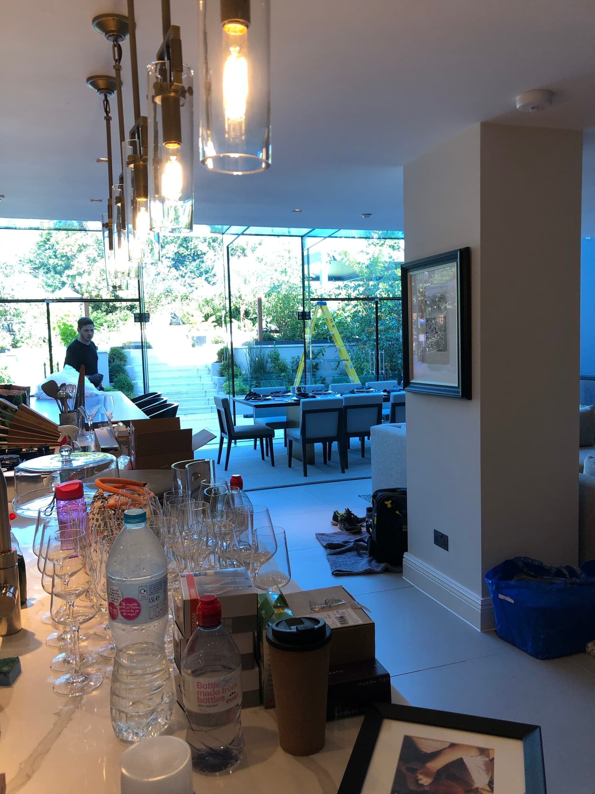 Dining furniture and glassware being installed, with the garden terrace beyond