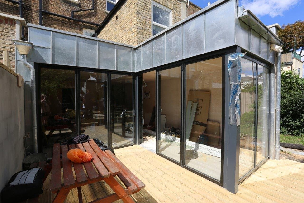 Completed glazed rear extension with steel-framed glass roof and bifold doors onto the garden
