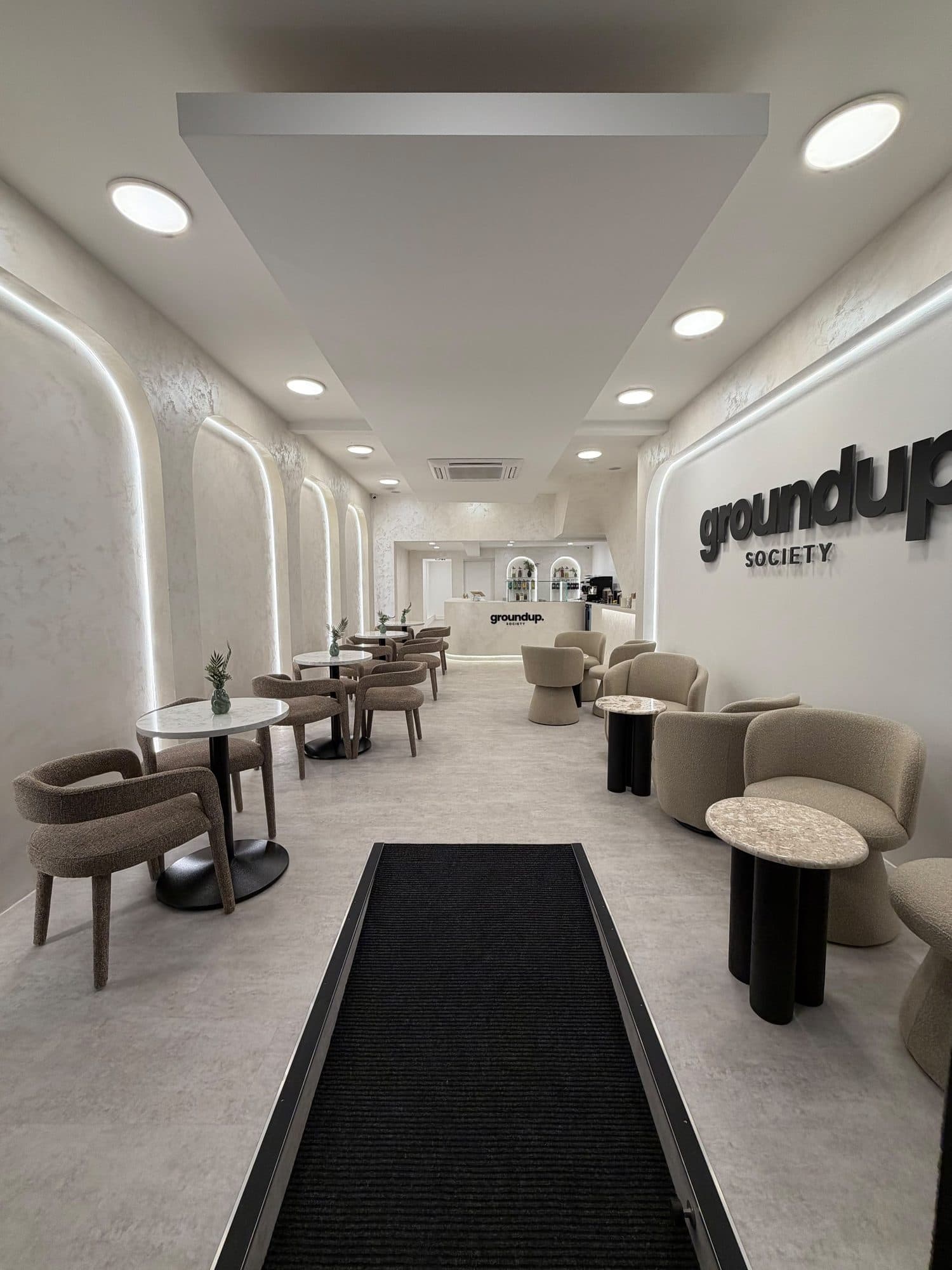 Finished Groundup Society commercial interior with illuminated arched wall features, seating and a curved reception counter