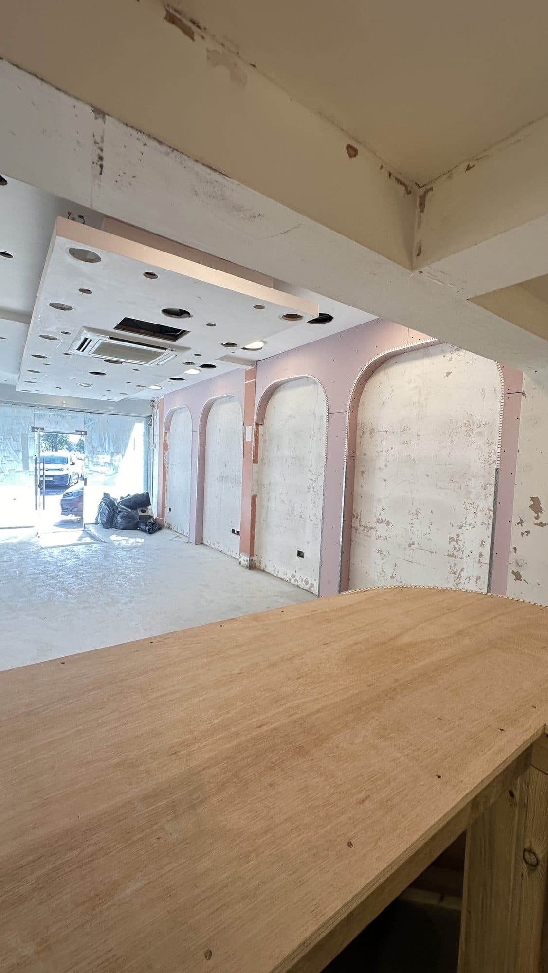 Long view down the unit during construction from the counter to the street entrance, showing the arch recesses and ceiling works in progress
