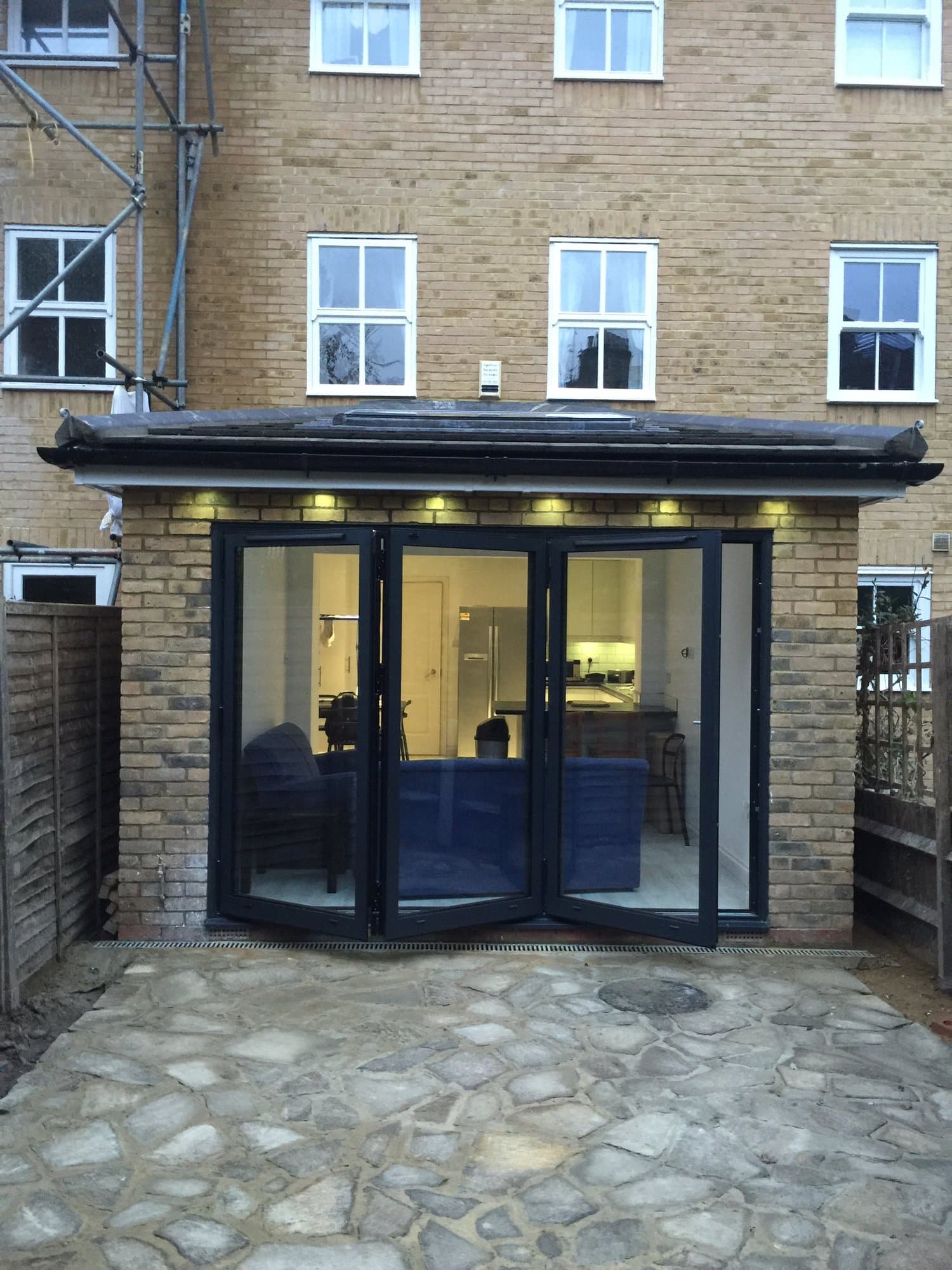 Rear extension at twilight with bifolding doors open onto the patio, kitchen and lounge lit inside