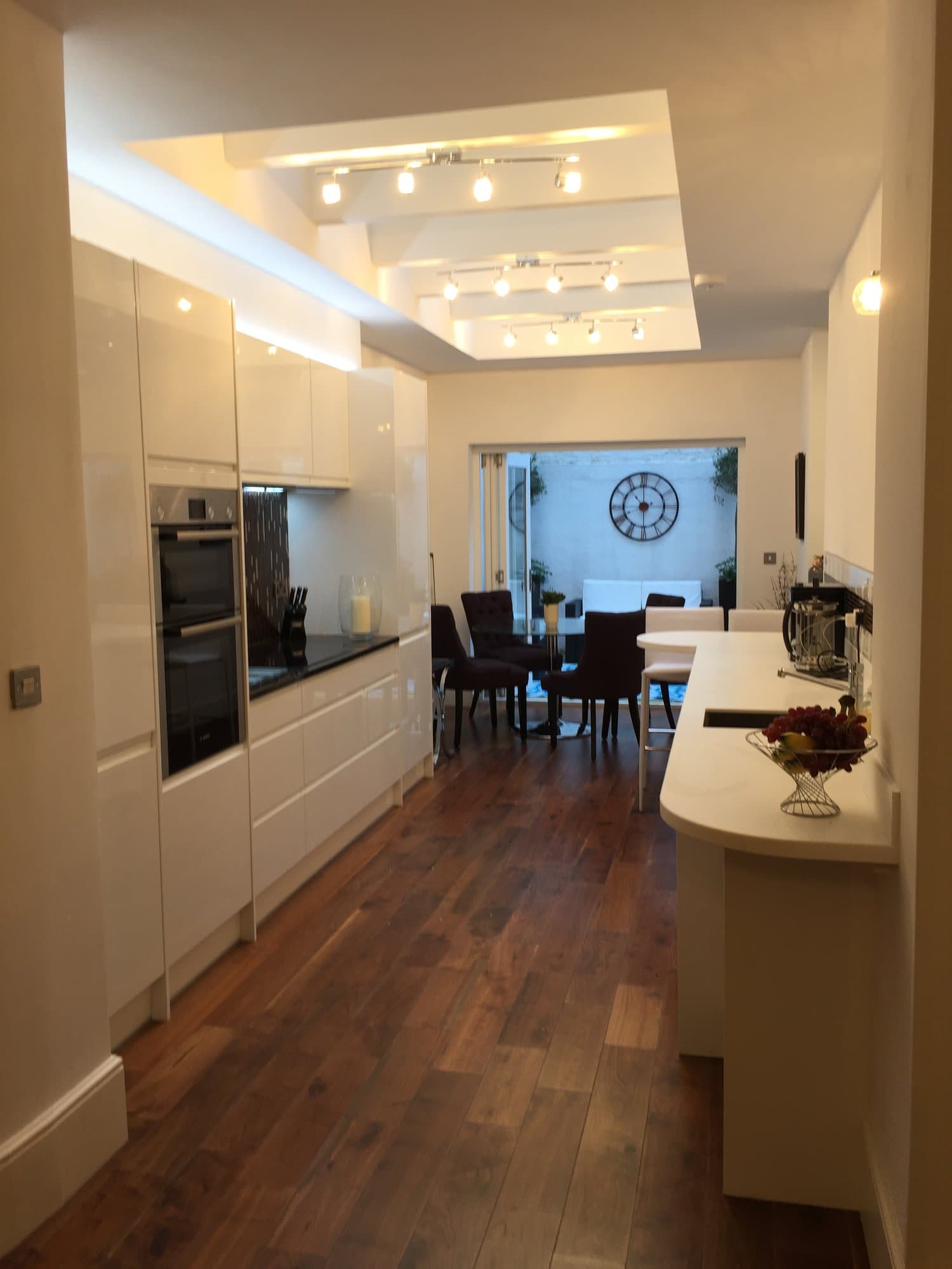 Galley kitchen with gloss white units opening onto a dining area