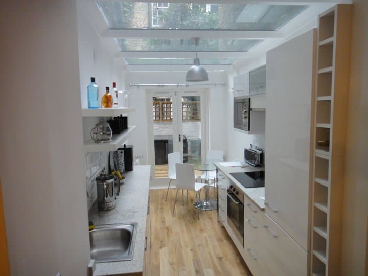 Narrow galley kitchen fitted beneath a fully glazed roof extension