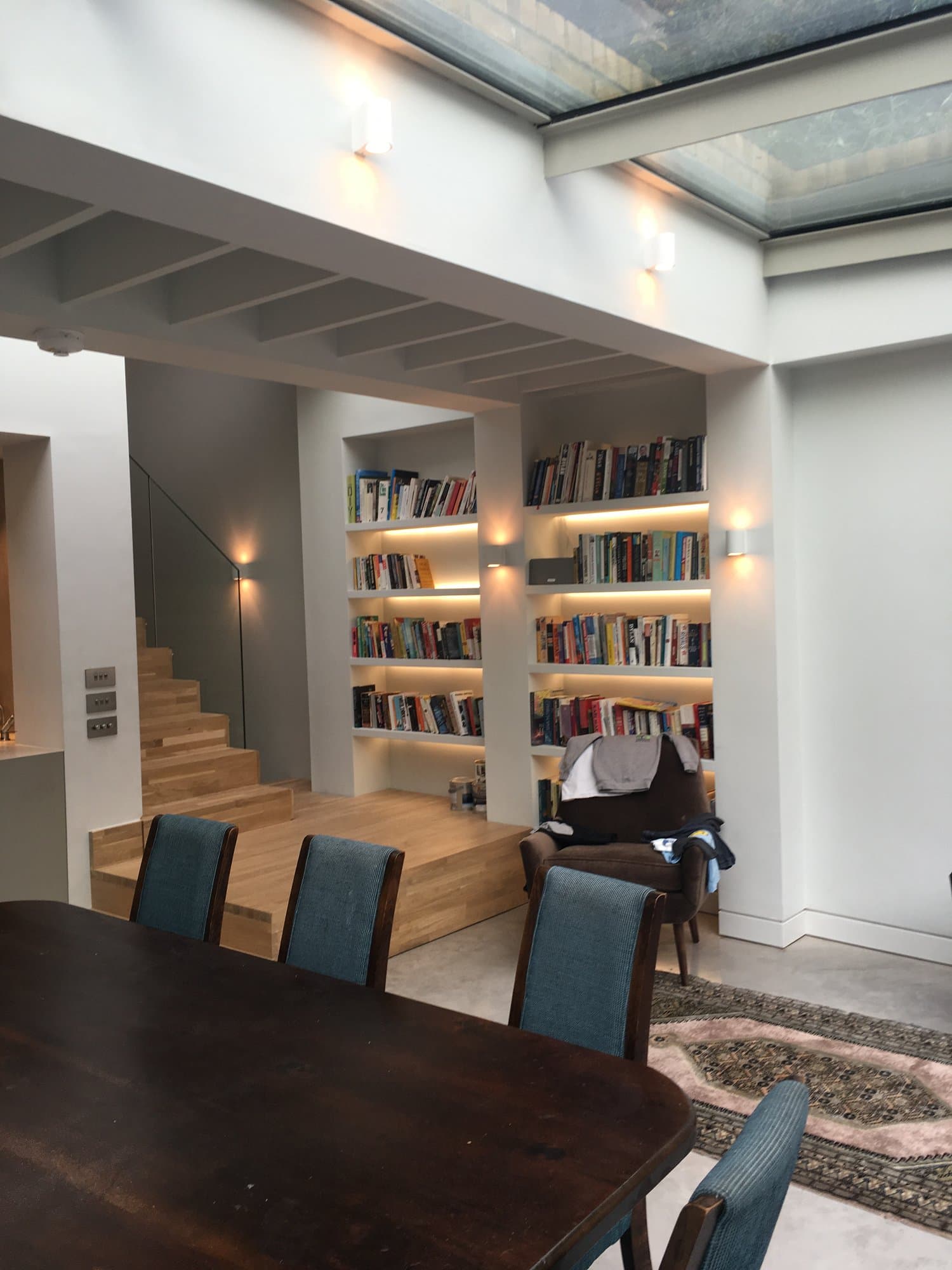 Double-height built-in bookshelves and staircase within the renovated house