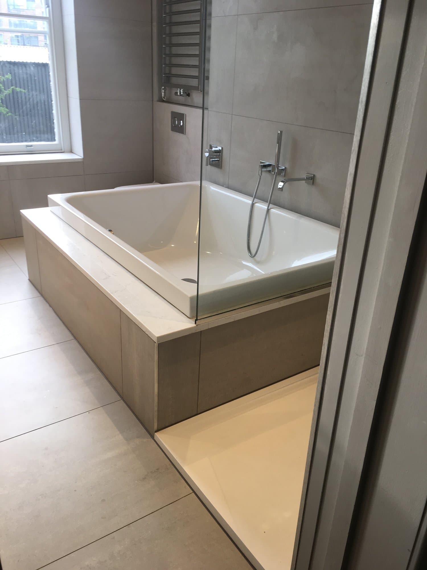 Bathroom with a built-in bath, marble surround and glass shower screen