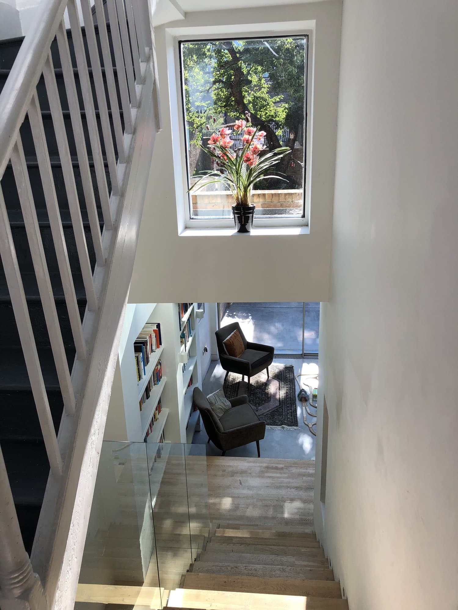 View down the stairwell past built-in bookshelves to the seating area below