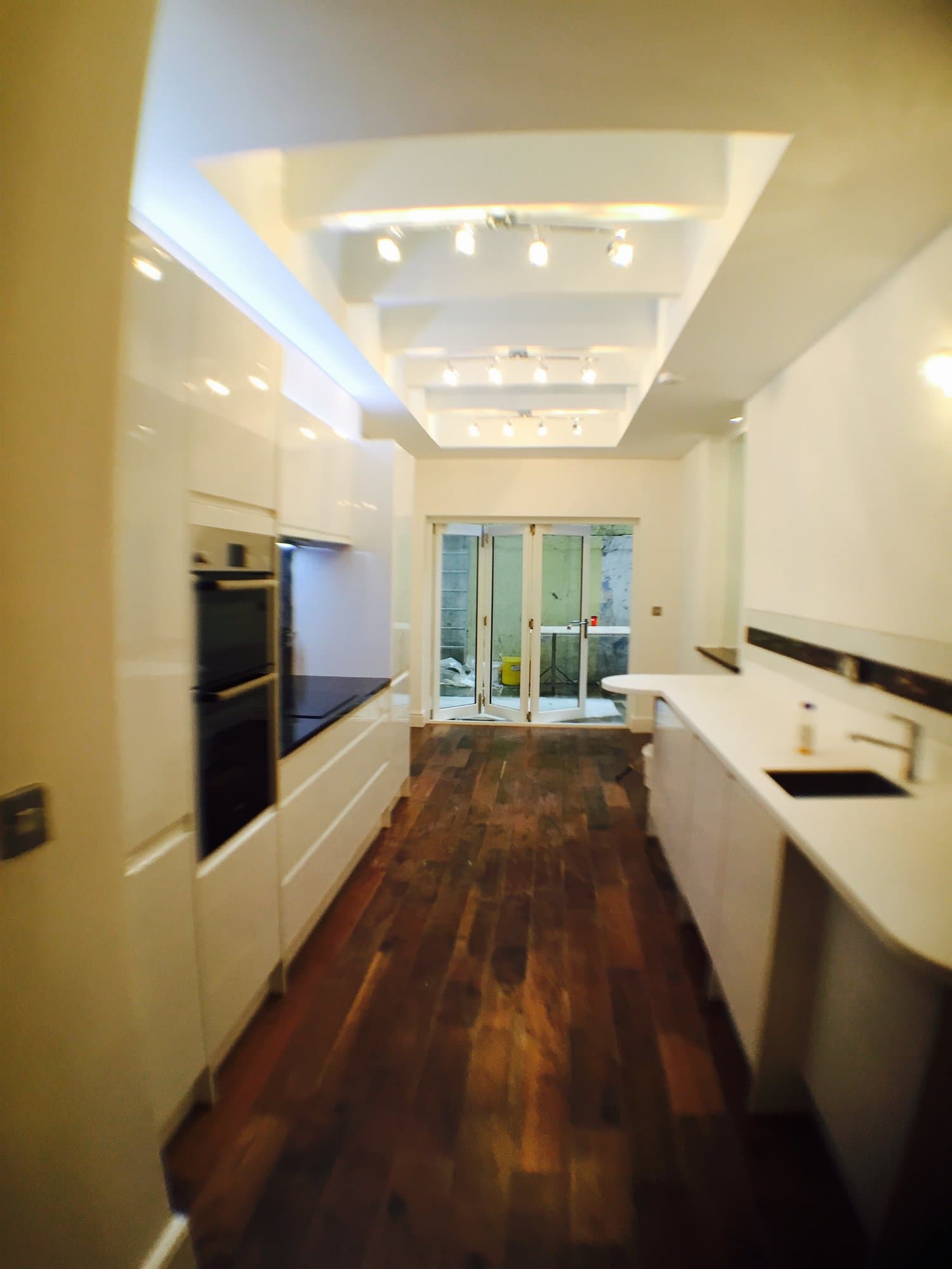 Newly remodelled luxury kitchen with high-gloss white cabinetry and dark hardwood flooring