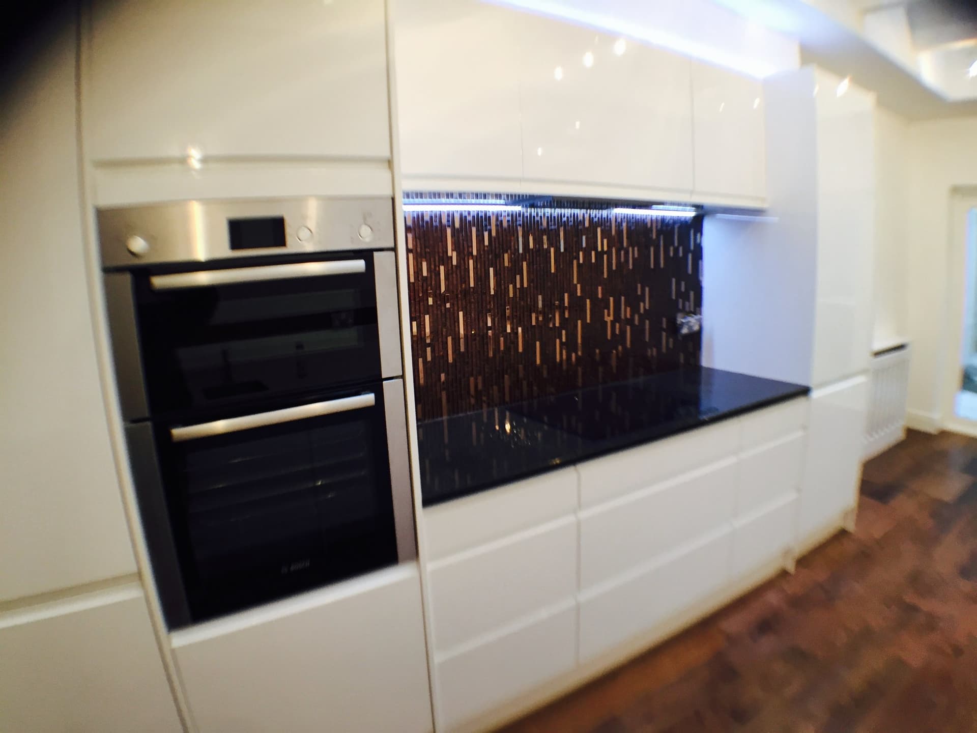 Integrated double oven and mosaic tile splashback with black quartz worktop