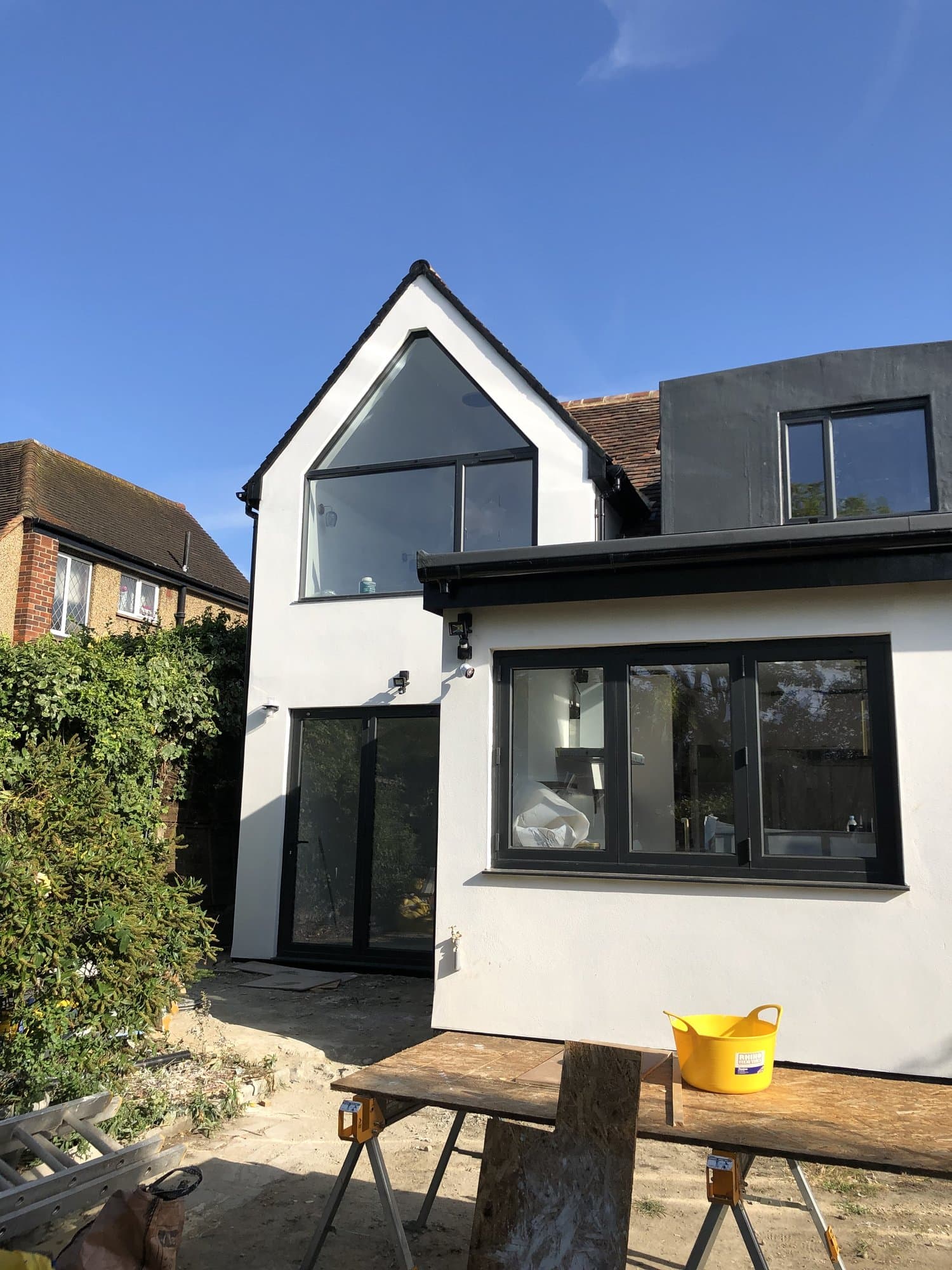 Double-storey side extension with a bay window feature, finished in white render with black-framed windows