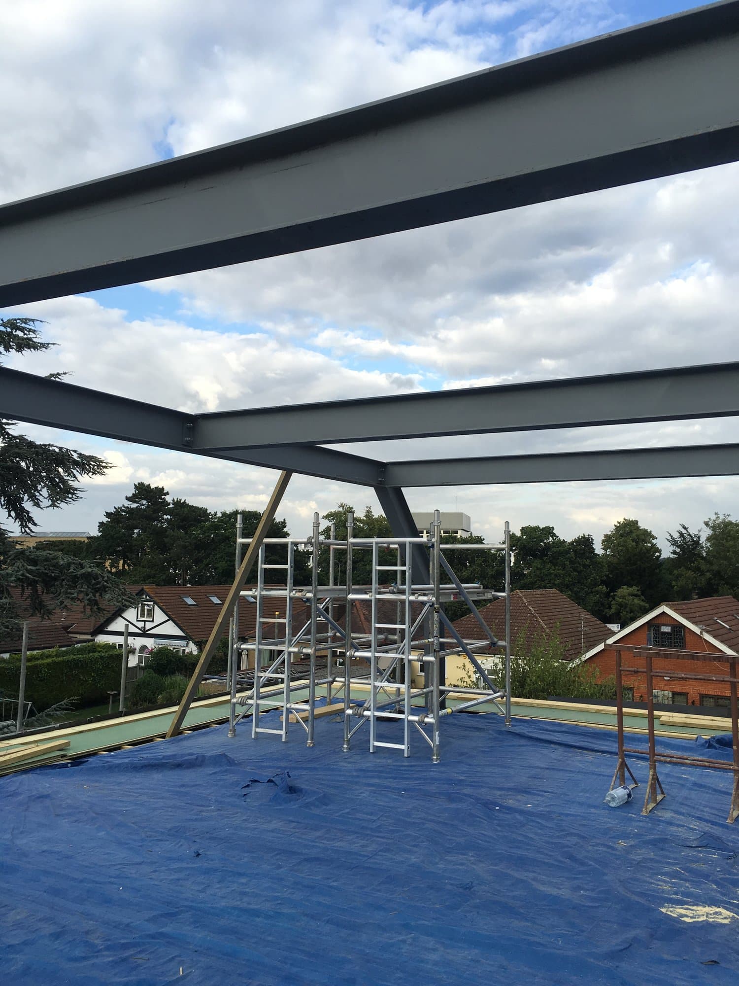 Steel beams viewed from below against the sky during installation